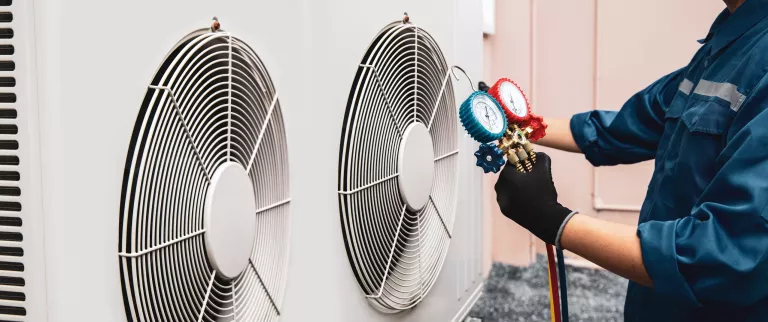 Heat and Air Conditioning, HVAC system service technician using measuring manifold gauge checking refrigerant and filling industrial air conditioner after duct cleaning maintenance outdoor compressor.